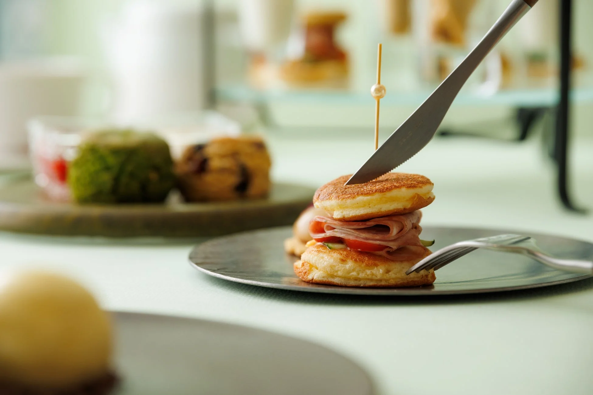 ミニパンケーキにハムと野菜が挟まれたサンドをナイフで切り分けている瞬間