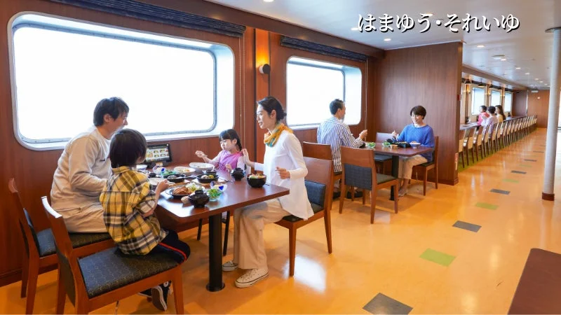 船内の明るいレストランで、家族連れや他の乗客が食事を楽しんでいる