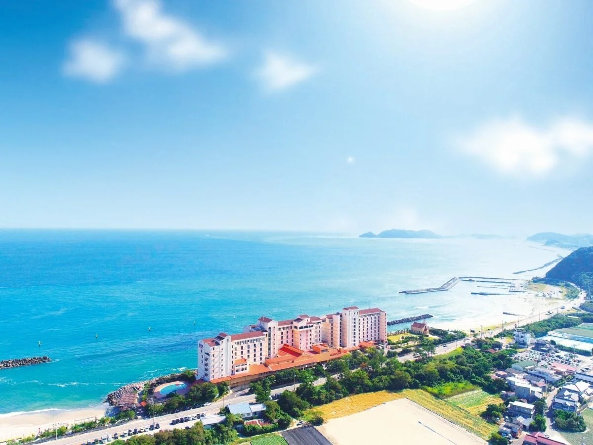 晴れた日に青い海と白い砂浜に面して建つリゾートホテル