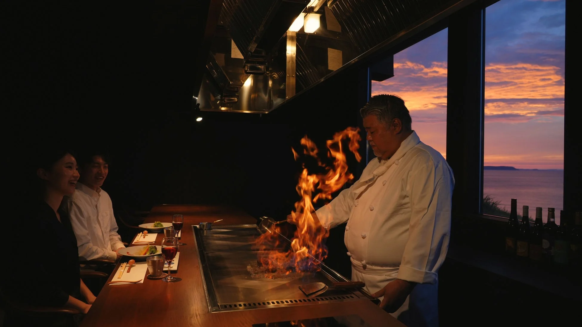 鉄板焼きレストランで炎を上げて調理するシェフ