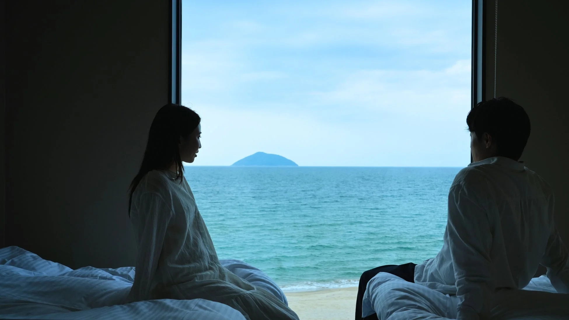 窓から広がる海と遠くの島を眺めるカップル