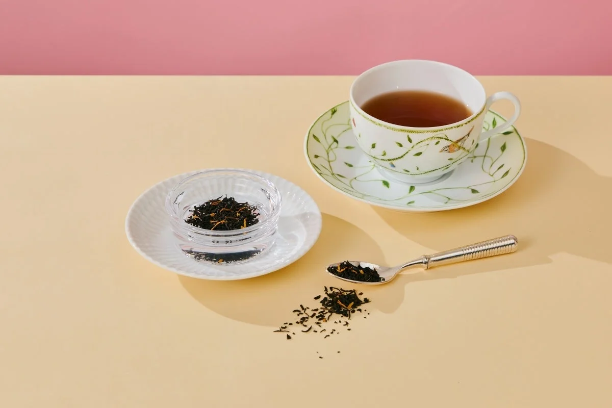 紅茶が入ったティーカップと茶葉、スプーンが配置されています。